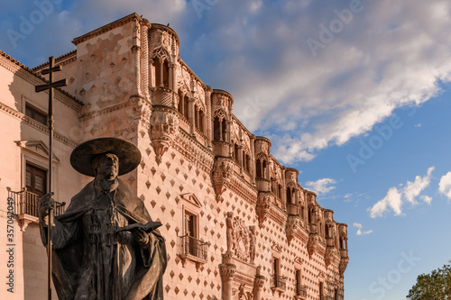 Statue of Cardinal Mendoza with the Palacio del Infantado in the background and a blue sky with clouds in the city of Guadalajara in Spain.