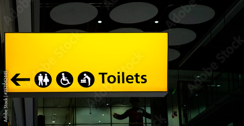 Yellow illuminated toilets and hand-washing sign for handicapped and able-bodied people in an airport.