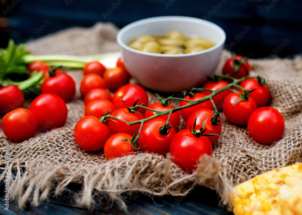 Red fresh tasty cherry tomatoes, spring onions, olives on dark rustic wooden background Red fresh tasty cherry tomatoes, spring onions, olives on dark rustic wooden background
