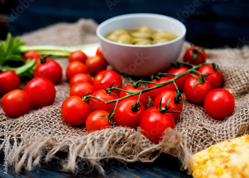 Red fresh tasty cherry tomatoes, spring onions, olives on dark rustic wooden background