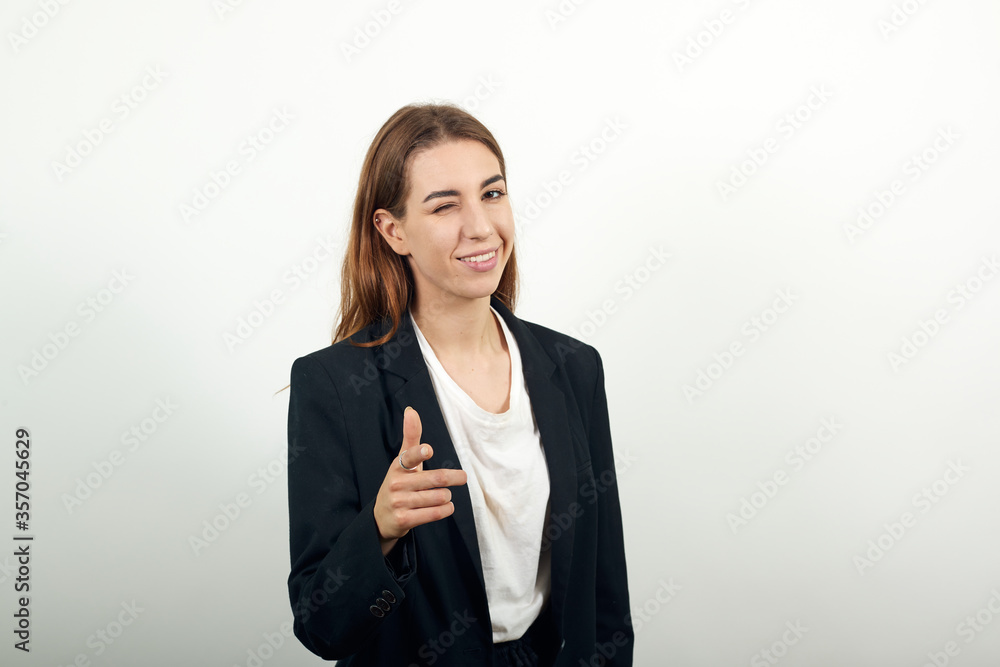 Showing thumb up, like sign positive something good has happened finger gesture for fine result well done. Winks an eye. Young attractive woman with brown hair in a light t-shirt and black jacket Showing thumb up, like sign positive something good has happened finger gesture for fine result well done. Winks an eye. Young attractive woman with brown hair in a light t-shirt and black jacket