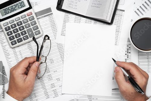 Top view of businessman working with financial statements. Modern black office desk with notebook, pencil and a lot of things. Flat lay table layout.