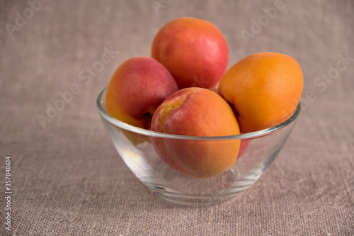 Fresh juicy apricots in a transparent glass plate. Macro.