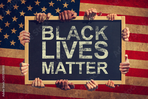 A lot of hand are holding a banner with text BLACK LIVES MATTER on background of American flag. Black lives matter photo