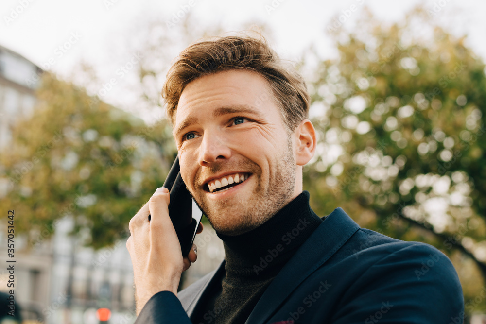 Smiling businessman talking through smart phone while looking away in city Smiling businessman talking through smart phone while looking away in city