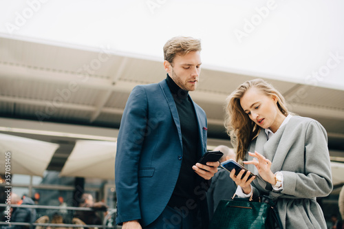 Low angle view of businesswoman using phone while standing by colleague in city photo