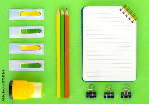 Flat lay with office or school stationery and supplies on bright green background. Top view, copy space. Back to school concept.