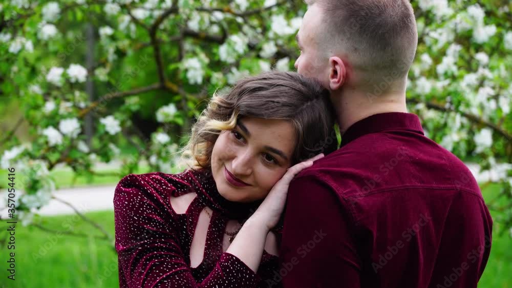 woman hugs her husband. In the background flowering apple tree woman hugs her husband. In the background flowering apple tree