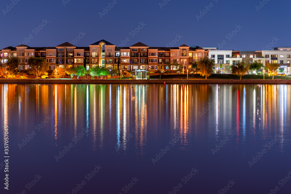 The multi-hued lights of stylish condos reflect off the calm waters of Tempe Town Lake in Arizona.