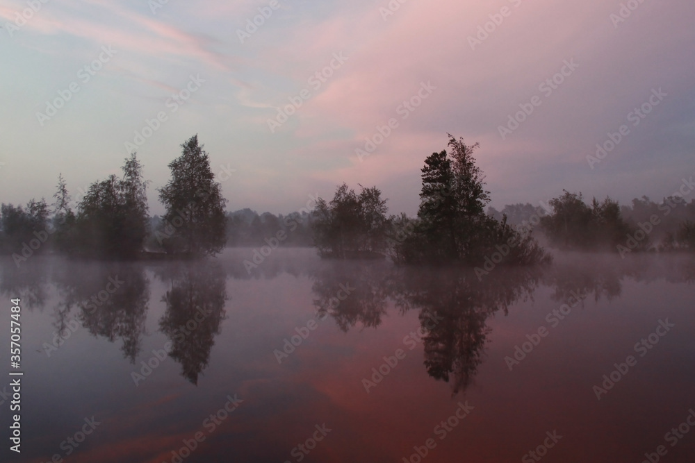 Blue-pink sunrise on the lake with morning mist