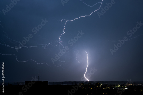 Beautiful night landscape with thunderstorm lightning bolts with rain and stormy sky over the city 