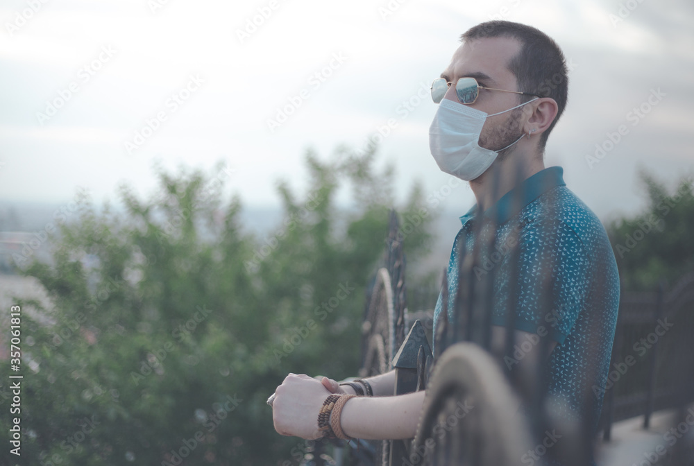 Young stylish man wears a protective mask and looking to sky, copy space