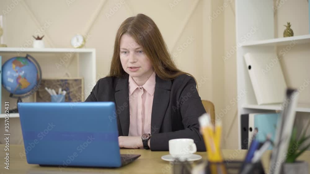 Redhead Caucasian woman sitting in front of laptop and talking. Portrait of beautiful female freelancer working remotely. Isolation, freelance, lifestyle, remote work, business. Redhead Caucasian woman sitting in front of laptop and talking. Portrait of beautiful female freelancer working remotely. Isolation, freelance, lifestyle, remote work, business.