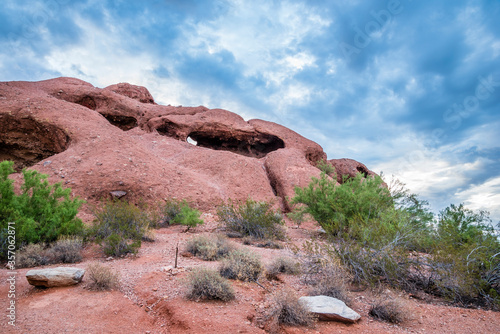 The unusual red sandstone rock formation known as Hole-in-the-Rock beneath a stormy sky. Papago Park in Phoenix, Arizona.