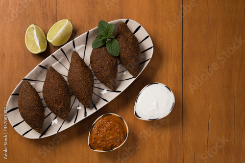 fried kibbeh served with yogurt sauce, and pepper sauce, on a plate photo