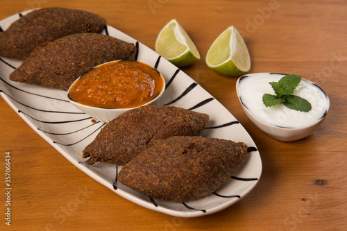 fried kibbeh served with pepper sauce, on a white plate. photo