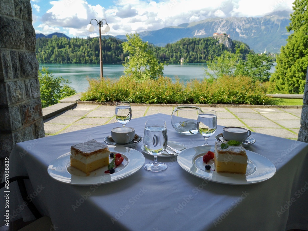 View of lake Bled castle and Alps mountains in background. Coffee and famous cream cake on the table. Luxury style in Slovenia with unique view