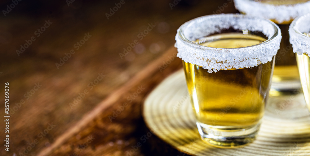 Tequila shot with lemon and sea salt on wooden background, selected focus Tequila shot with lemon and sea salt on wooden background, selected focus