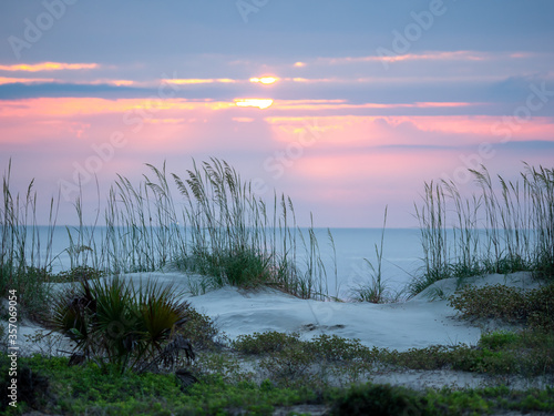 sunrise at the beach with sun peaking over sand dunes