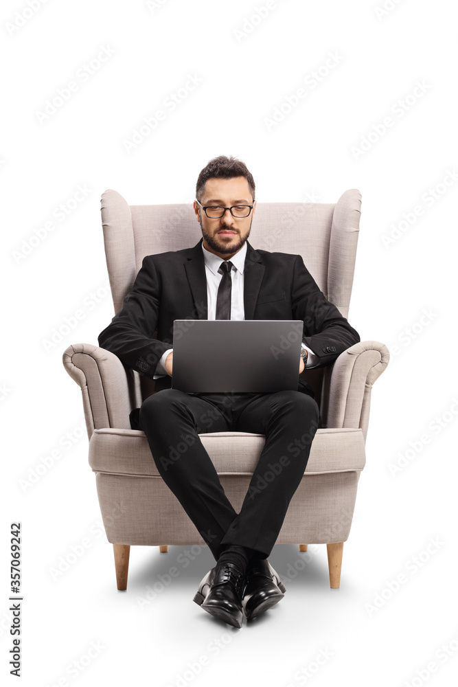 Businessman siting in an armchair and working on a laptop computer Businessman siting in an armchair and working on a laptop computer