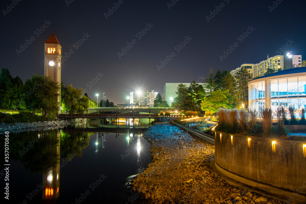 The Clock Tower illuminated next to the Spokane River and carousel in the Riverfront Park area of downtown Spokane, Washington, USA late at night.