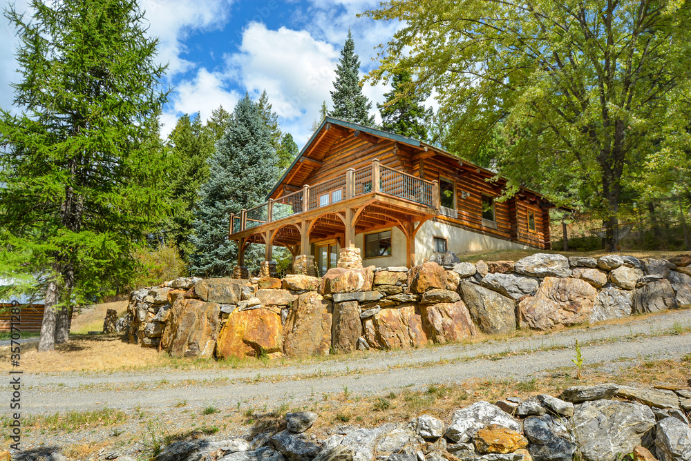 A picturesque rustic log home in the mountains surrounded by pine trees on a rocky hillside in Coeur d'Alene, Idaho. A picturesque rustic log home in the mountains surrounded by pine trees on a rocky hillside in Coeur d'Alene, Idaho.