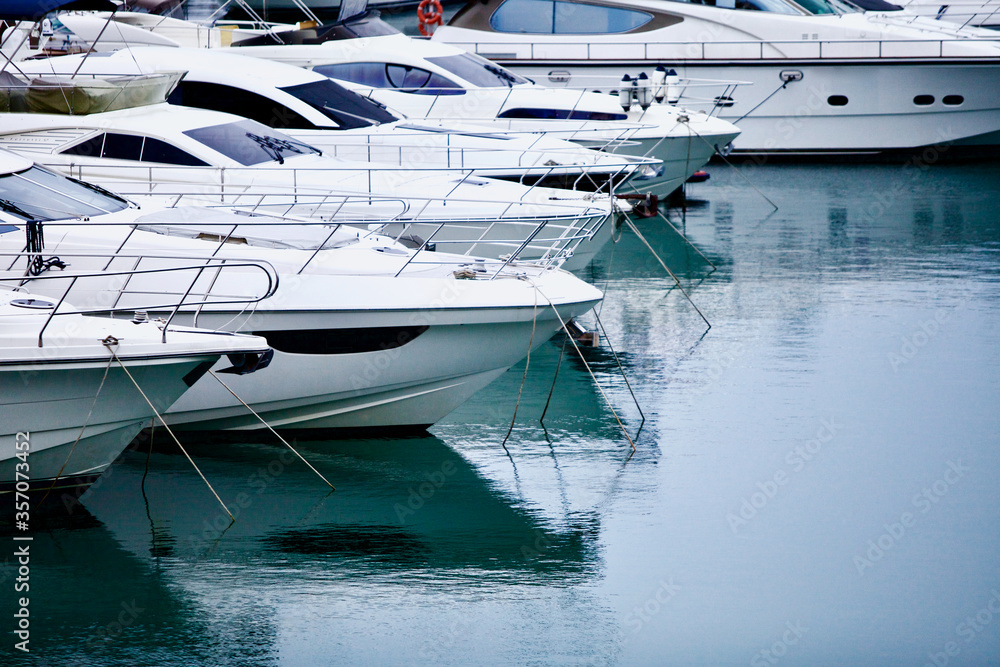Yachts and speed boats at harbor. Yachts moored in the port. Ocean Coast pier. High class lifestyle. Yachting. Expensive toys. Sea ​​transport. Nautical. Yachting sport. Expensive yachts at the pier.