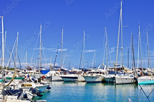 Yachts and speed boats at harbor. Yachts moored in the port. Ocean Coast pier. High class lifestyle. Yachting. Expensive toys. Sea ​​transport. Nautical. Yachting sport. Expensive yachts at the pier. © ST-art
