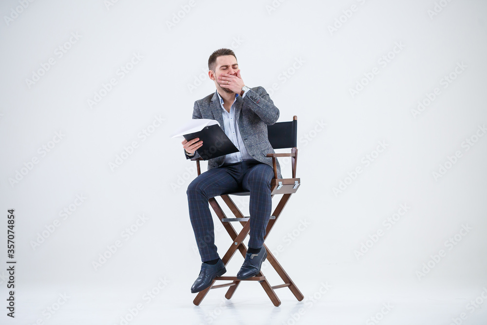 Business man businessman in a suit sitting on a wooden chair and throws documents. On a white background with thoughts of a new project Business man businessman in a suit sitting on a wooden chair and throws documents. On a white background with thoughts of a new project
