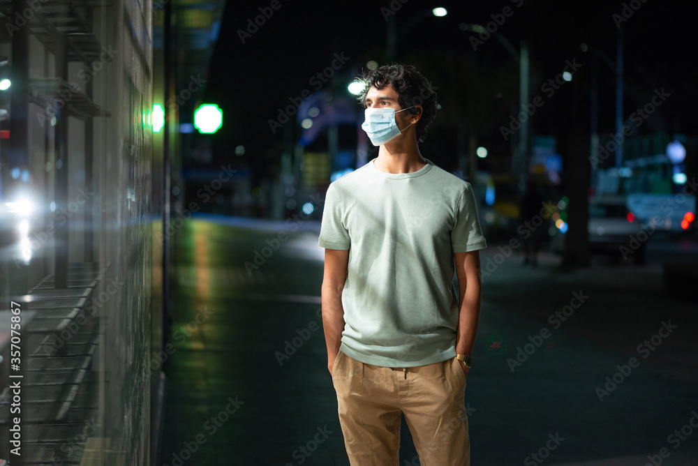 Handsome young man with face mask walks looking at empty shelves in a shop on city street at night Handsome young man with face mask walks looking at empty shelves in a shop on city street at night