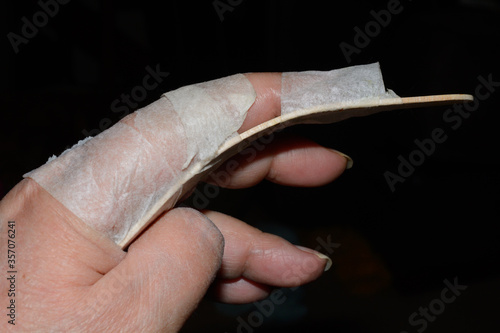 Homemade finger brace or splint for index finger injury made from slightly curved popsicle stick and paper tape