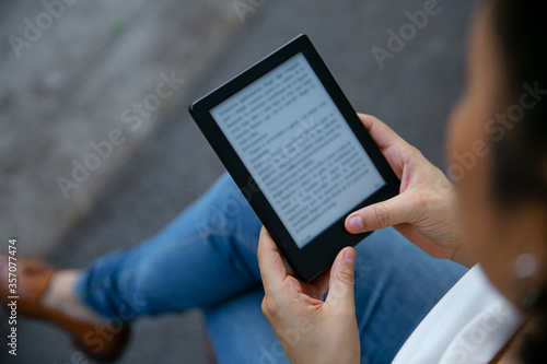 young latin woman reading an ebook on digital tablet device. Focus on the ebook. photo