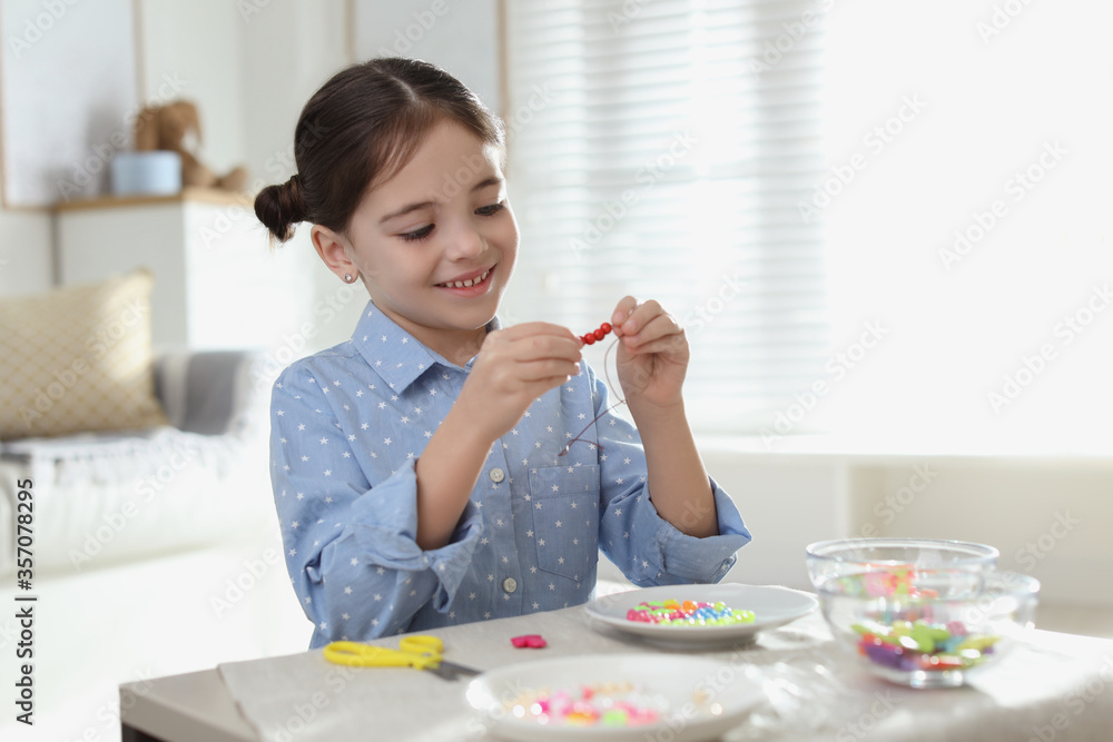 Little girl making accessory with beads at table indoors. Creative hobby Little girl making accessory with beads at table indoors. Creative hobby