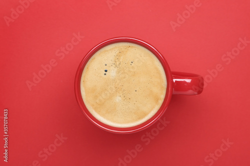 Cup of aromatic coffee on red background, top view