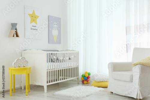 Stylish baby room interior with crib and cute pictures on wall © New Africa