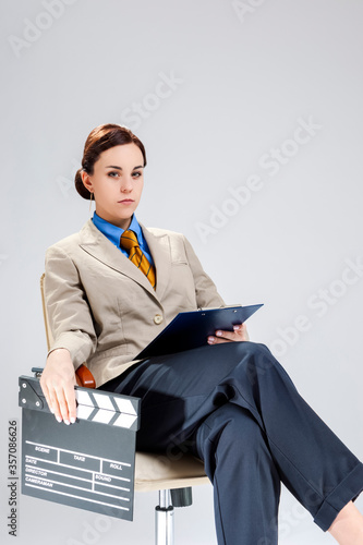 Filmmaking and Movie Concepts. Portrait of Serious Professional Female Film Director Posing with Actioncut. Sitting in Chair with Notepad. photo