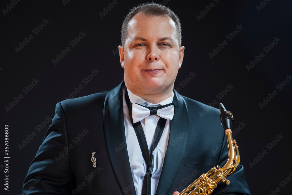 Naklejka premium Portrait of Tranquil Male Saxophonist Player Against Black