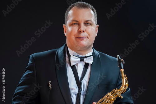 Portrait of Tranquil Male Saxophonist Player Against Black