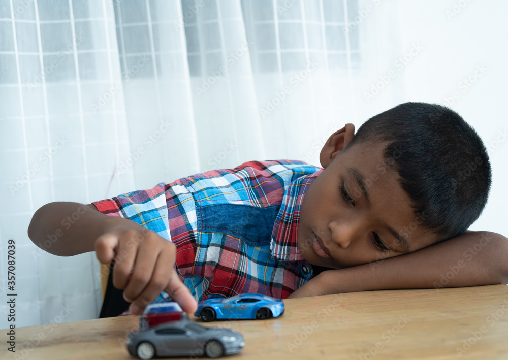 Sad boy lying on the table and play toy car Sad boy lying on the table and play toy car