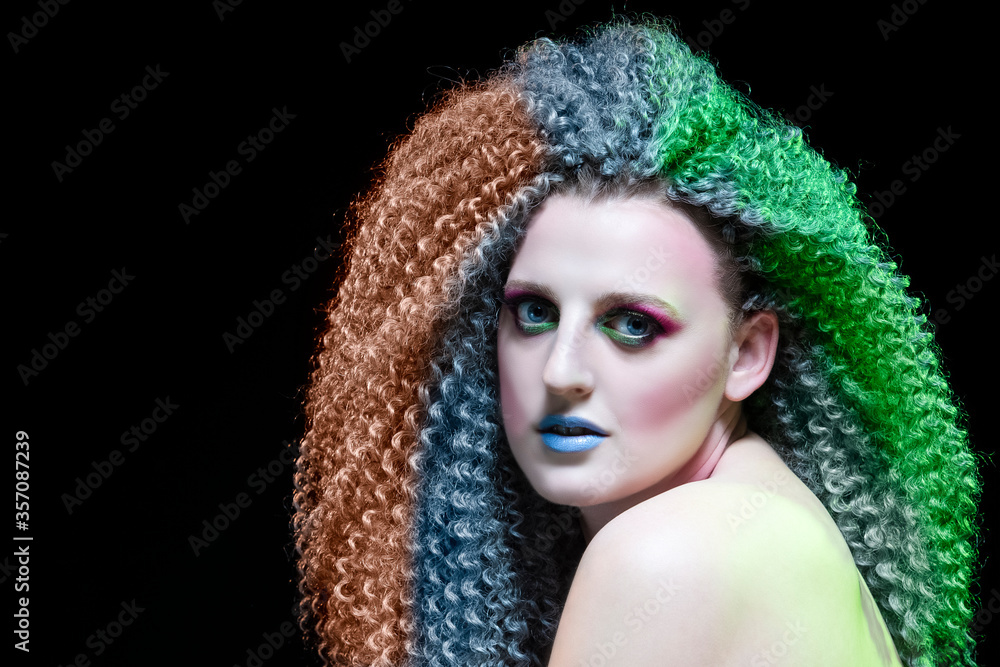 Creative Ideas. Caucasian Girl With Frizzy Colorful Hair and Artistic Eyes Makeup. Posing Against Black. Creative Ideas. Caucasian Girl With Frizzy Colorful Hair and Artistic Eyes Makeup. Posing Against Black.