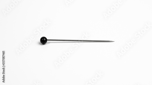 One pin with round black head on white background.