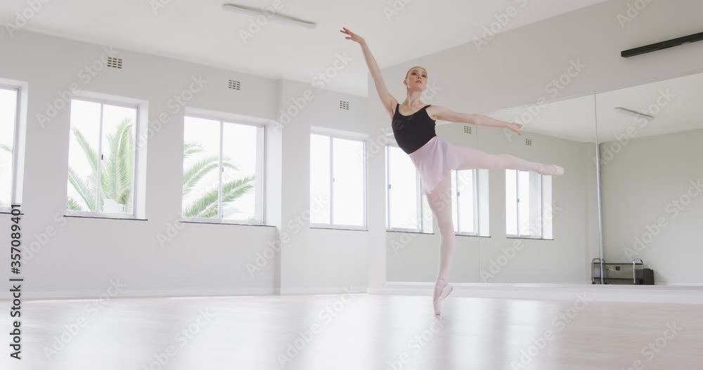 Caucasian female ballet dancer practicing ballet during a dance class in a bright studio Caucasian female ballet dancer practicing ballet during a dance class in a bright studio