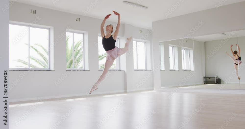Caucasian female ballet dancer practicing ballet during a dance class in a bright studio Caucasian female ballet dancer practicing ballet during a dance class in a bright studio