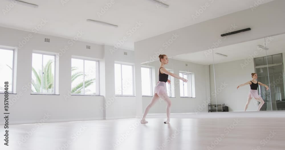 Caucasian female ballet dancer practicing ballet during a dance class in a bright studio Caucasian female ballet dancer practicing ballet during a dance class in a bright studio