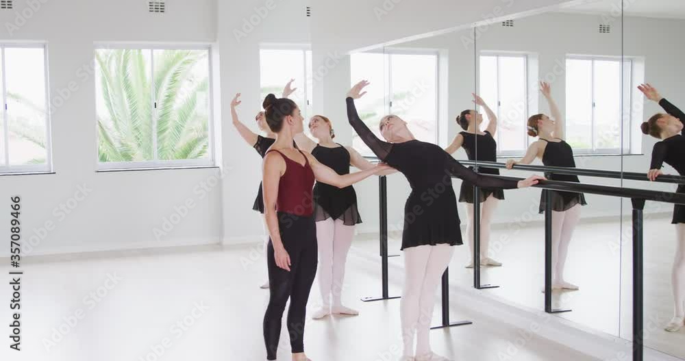 Caucasian ballet female dancers exercising with a barre by a mirror during a ballet class Caucasian ballet female dancers exercising with a barre by a mirror during a ballet class