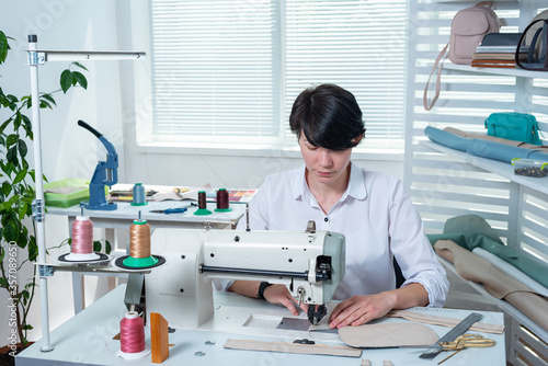 seamstress girl is at the workplace behind the sewing machine