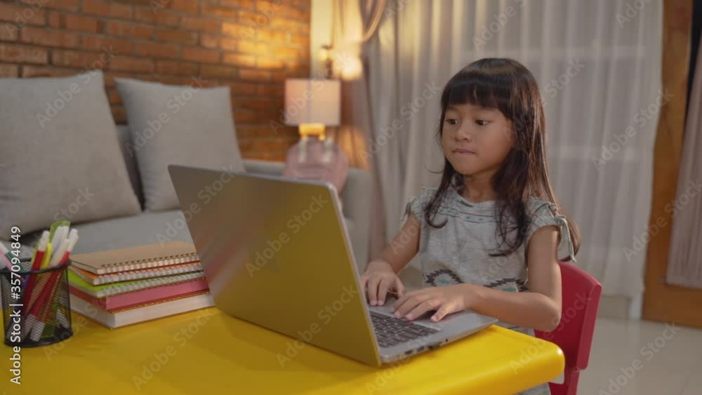happy little girl doing homework using laptop at home happy little girl doing homework using laptop at home
