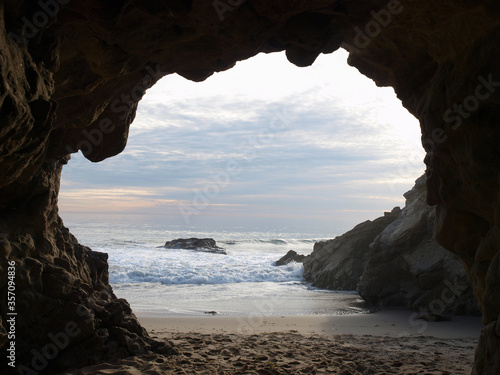 Pacific ocean sea cave with cloudy sky near Malibu in Southern California.