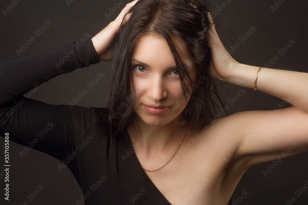 portrait of a brunette on a dark gray studio background in a black dress