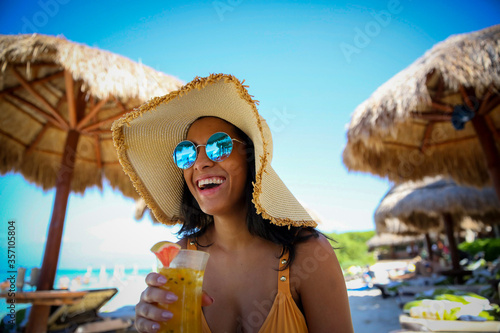 smiling woman on beach drinking a cocktail photo